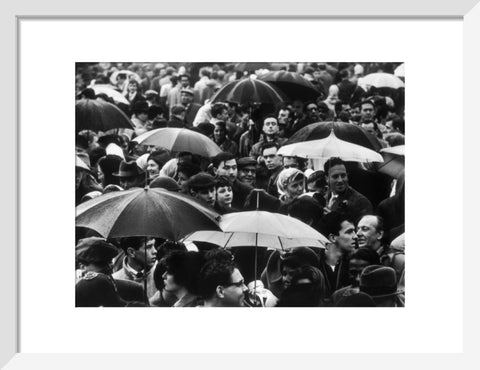 A crowd huddled underneath umbrellas in the rain 1961