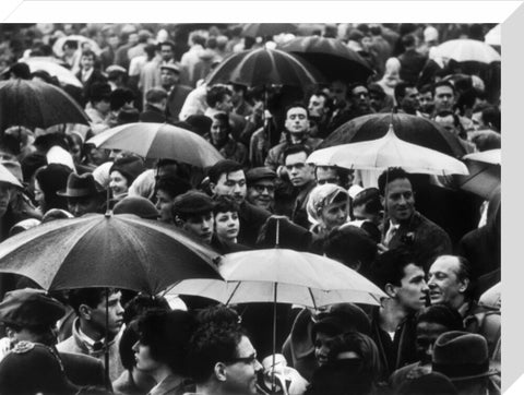 A crowd huddled underneath umbrellas in the rain 1961