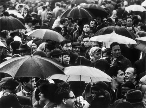 A crowd huddled underneath umbrellas in the rain 1961