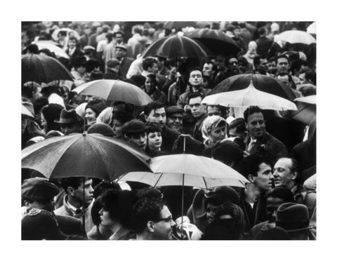 A crowd huddled underneath umbrellas in the rain 1961