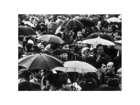 A crowd huddled underneath umbrellas in the rain 1961