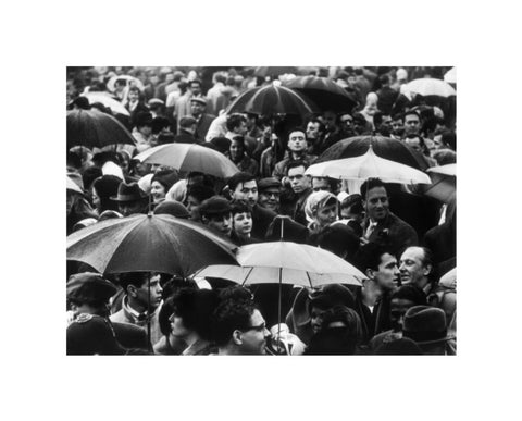 A crowd huddled underneath umbrellas in the rain 1961