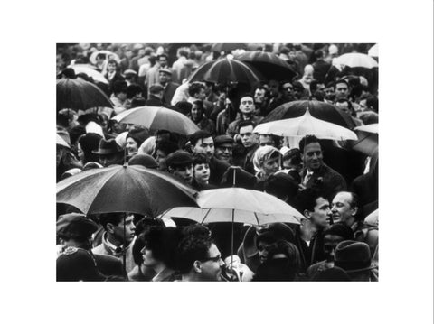 A crowd huddled underneath umbrellas in the rain 1961