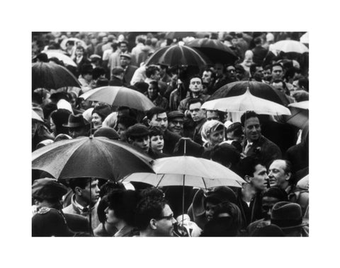 A crowd huddled underneath umbrellas in the rain 1961