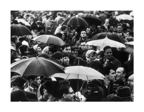 A crowd huddled underneath umbrellas in the rain 1961