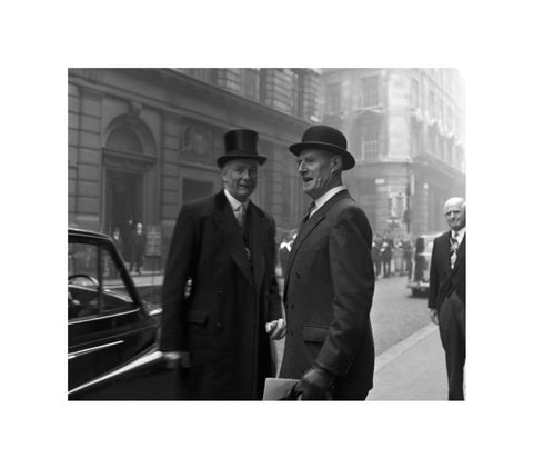 Three formally dressed men on a street flanked by high buildings. c.1955