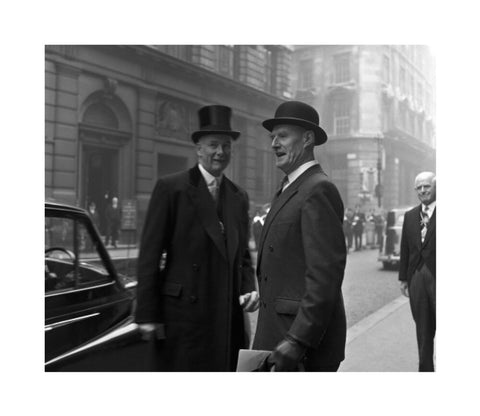 Three formally dressed men on a street flanked by high buildings. c.1955