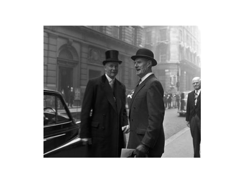 Three formally dressed men on a street flanked by high buildings. c.1955