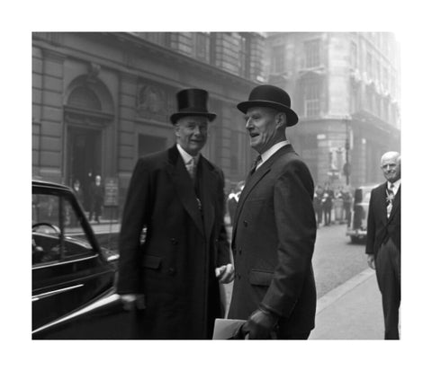 Three formally dressed men on a street flanked by high buildings. c.1955