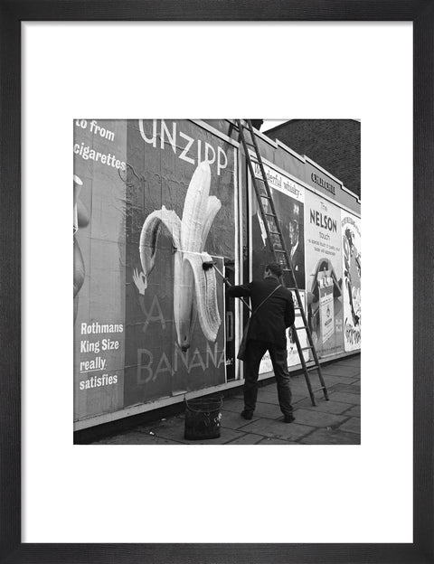 Man pastes up a billboard advertisement. c.1955