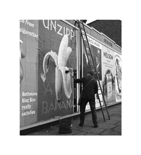 Man pastes up a billboard advertisement. c.1955