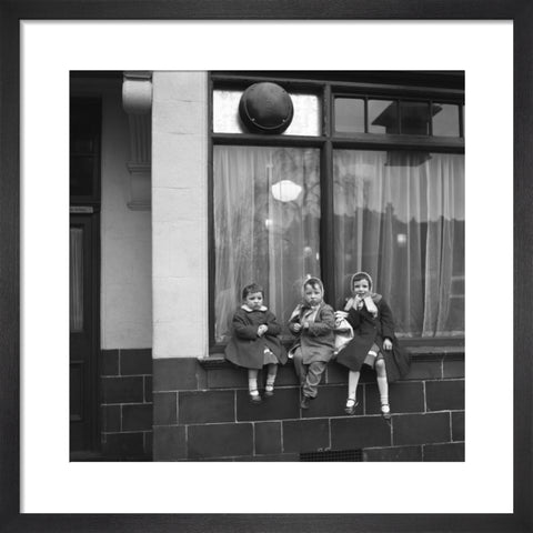 Three children perched on the windowsill of a pub. c.1955