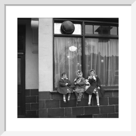 Three children perched on the windowsill of a pub. c.1955