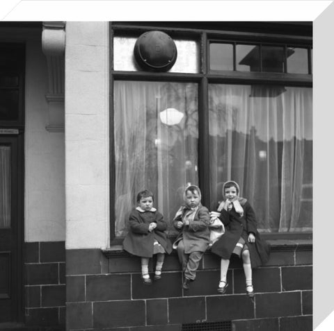 Three children perched on the windowsill of a pub. c.1955