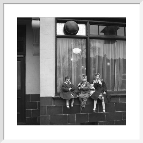 Three children perched on the windowsill of a pub. c.1955