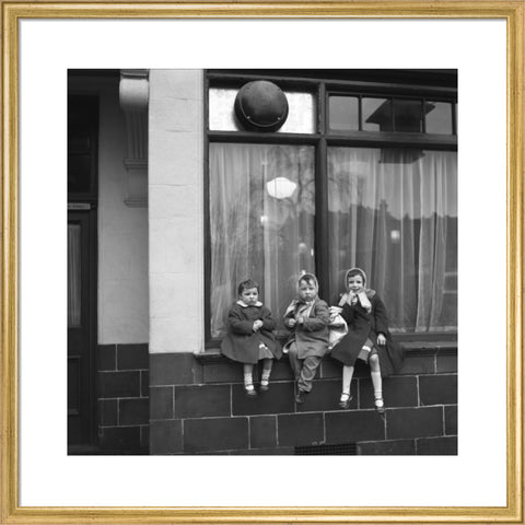 Three children perched on the windowsill of a pub. c.1955