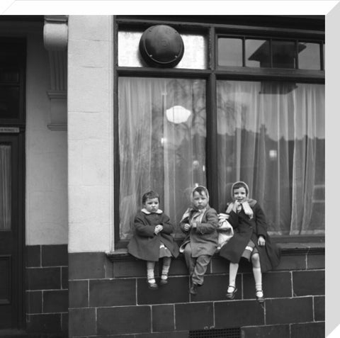 Three children perched on the windowsill of a pub. c.1955