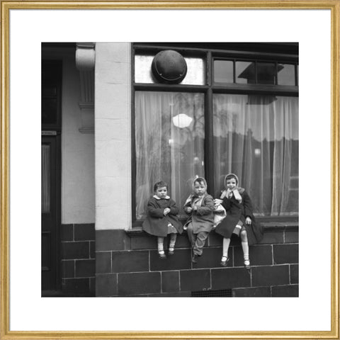 Three children perched on the windowsill of a pub. c.1955