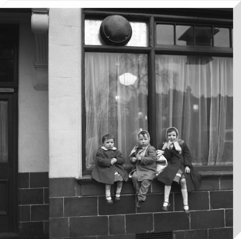 Three children perched on the windowsill of a pub. c.1955