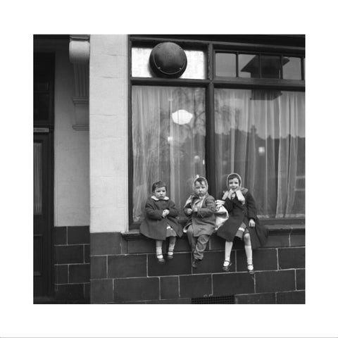 Three children perched on the windowsill of a pub. c.1955