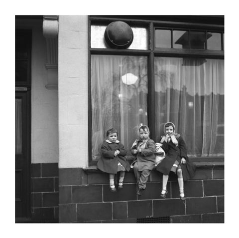 Three children perched on the windowsill of a pub. c.1955