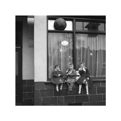 Three children perched on the windowsill of a pub. c.1955