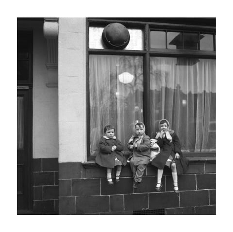 Three children perched on the windowsill of a pub. c.1955