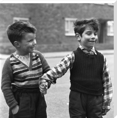 Two boys hold hands in street. c.1955