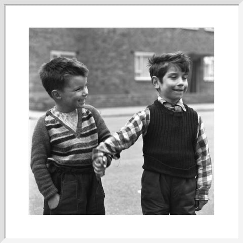 Two boys hold hands in street. c.1955